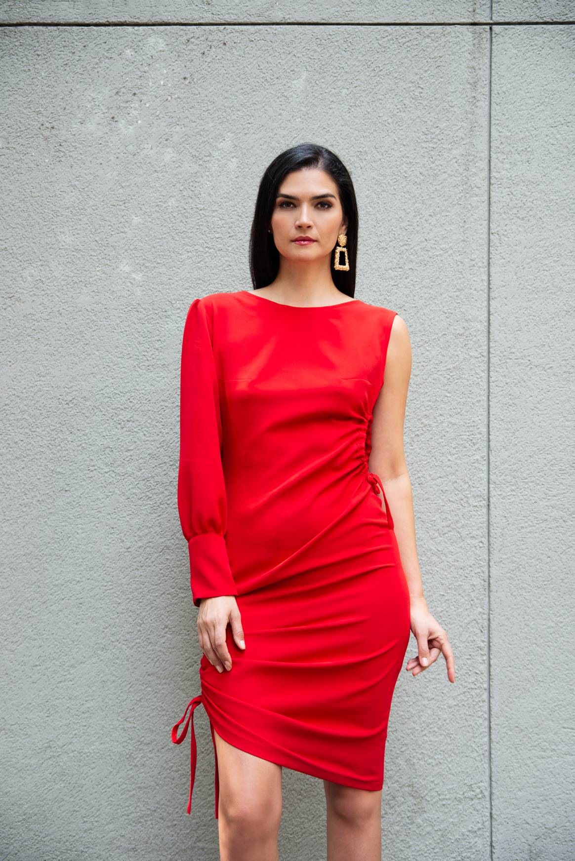 Vestido rojo de crepé con elastano, corte asimétrico, de una sola manga ligeramente abullonada, con una apertura en un costado, y escote redondo hasta la media espalda