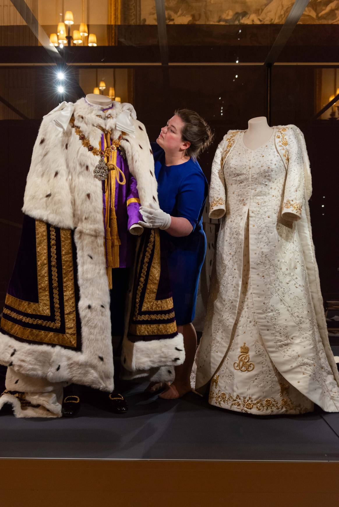 Curator Sally Goodsir makes final adjustments to  The King’s Robe of Estate shown next to  The Queen’s Coronation Dress