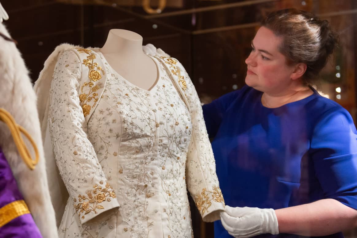 Curator Sally Goodsir makes final adjustments to  The Queen’s Coronation Dress in a special  Coronation display for visitors to the Summer  Opening of Buckingham Palace