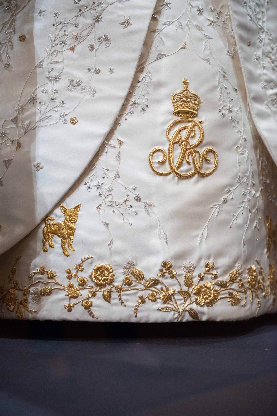 A close-up of embroidered details on The Queen’s Coronation Dress, including one of Her Majesty’s Jack Russell Terriers and the name of one of her grandchildren