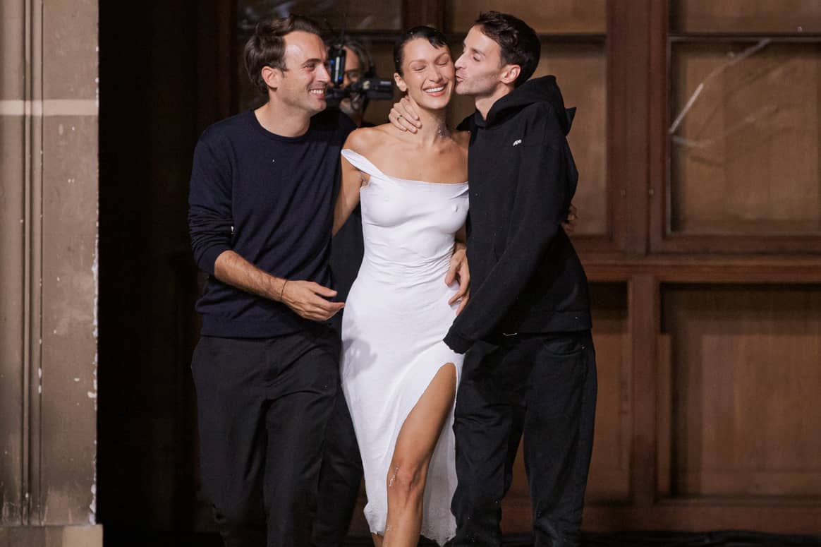 Bella Hadid wearing Coperni’s SS23 spray paint dress is being hugged by designers Sébastien Meyer and Arnaud Vaillant. (Photo: Coperni)