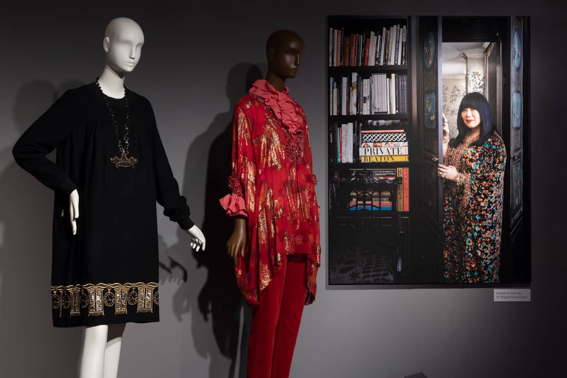 Ein Foto von Anna Sui von Miguel Flores-Vianna neben einem Kleid der Designerin mit einer Halskette von Eric Beamon, 1997, und einem Kaftan-Ensemble, 2012, von Anna Sui. Foto: The Museum at FIT