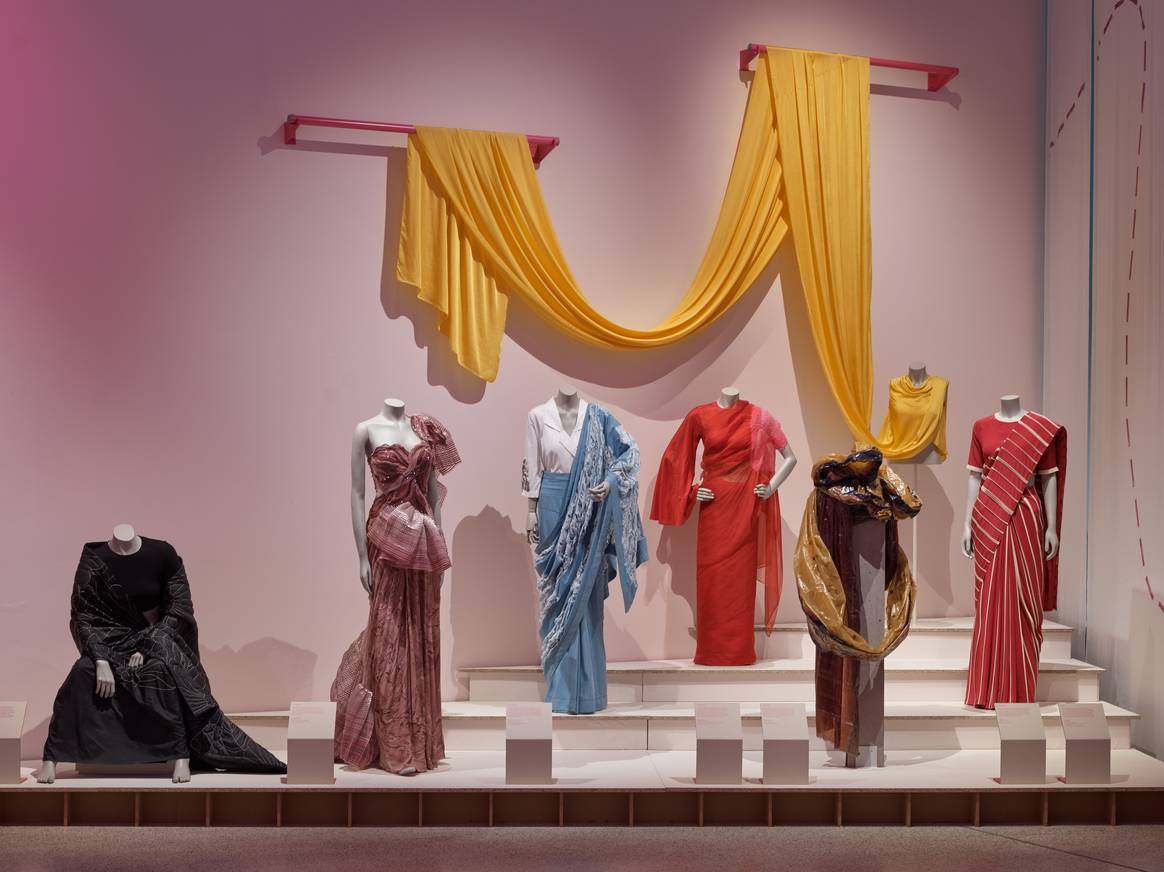 Wie lang ein Sari sein kann, zeigt das gelbe, an der Wand drapierte Modell. Sechs Beispiele von “Offbeat Saris”. Bild: Andy Stagg / Design Museum