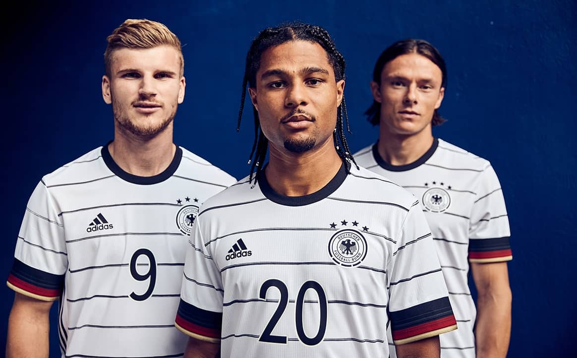 Das Heimtrikot der deutschen Fußball-Nationalmannschaft setzt für die EM auf ein schlichtes weißes Trikot mit schmalen, schwarzen Horizontalstreifen, die mit Akzenten in den Nationalfarben an den Ärmeln ergänzt werden. Foto: Adidas